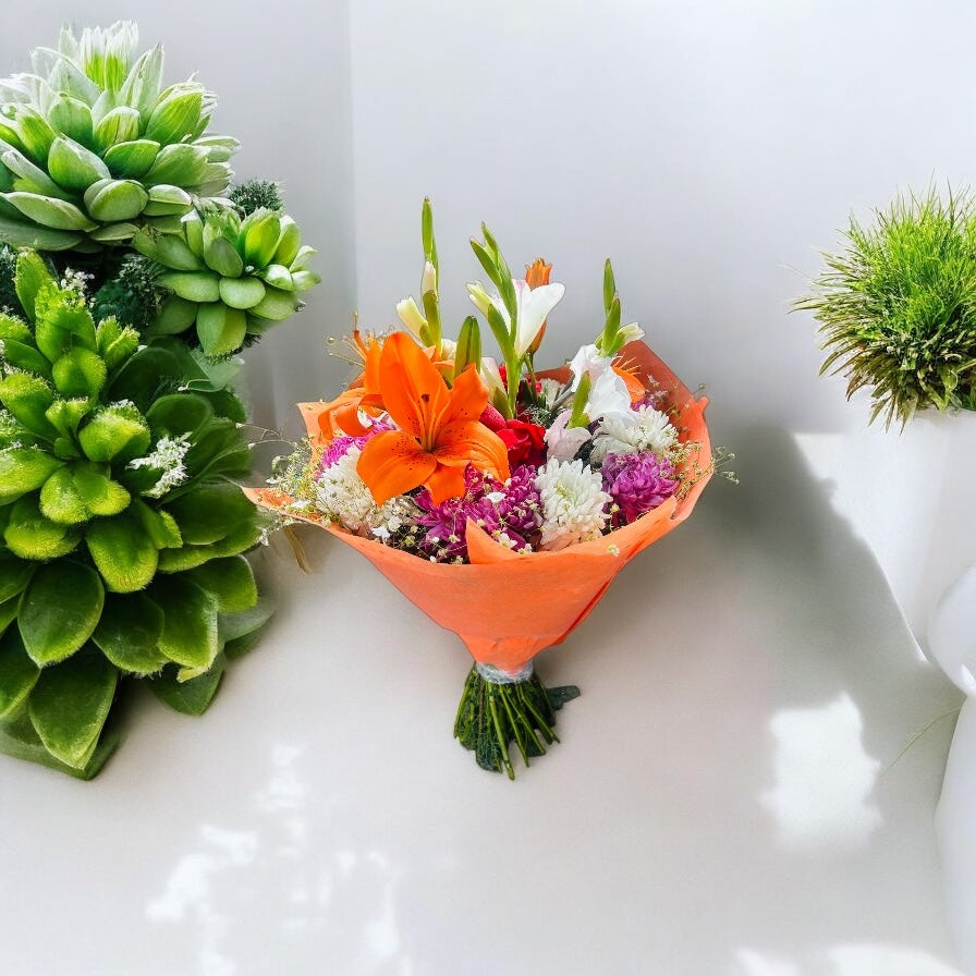 Elegant fresh flower bouquet with lilies, roses, carnations, chrysanthemums, and tuberoses wrapped in orange – perfect for gifting on special occasions