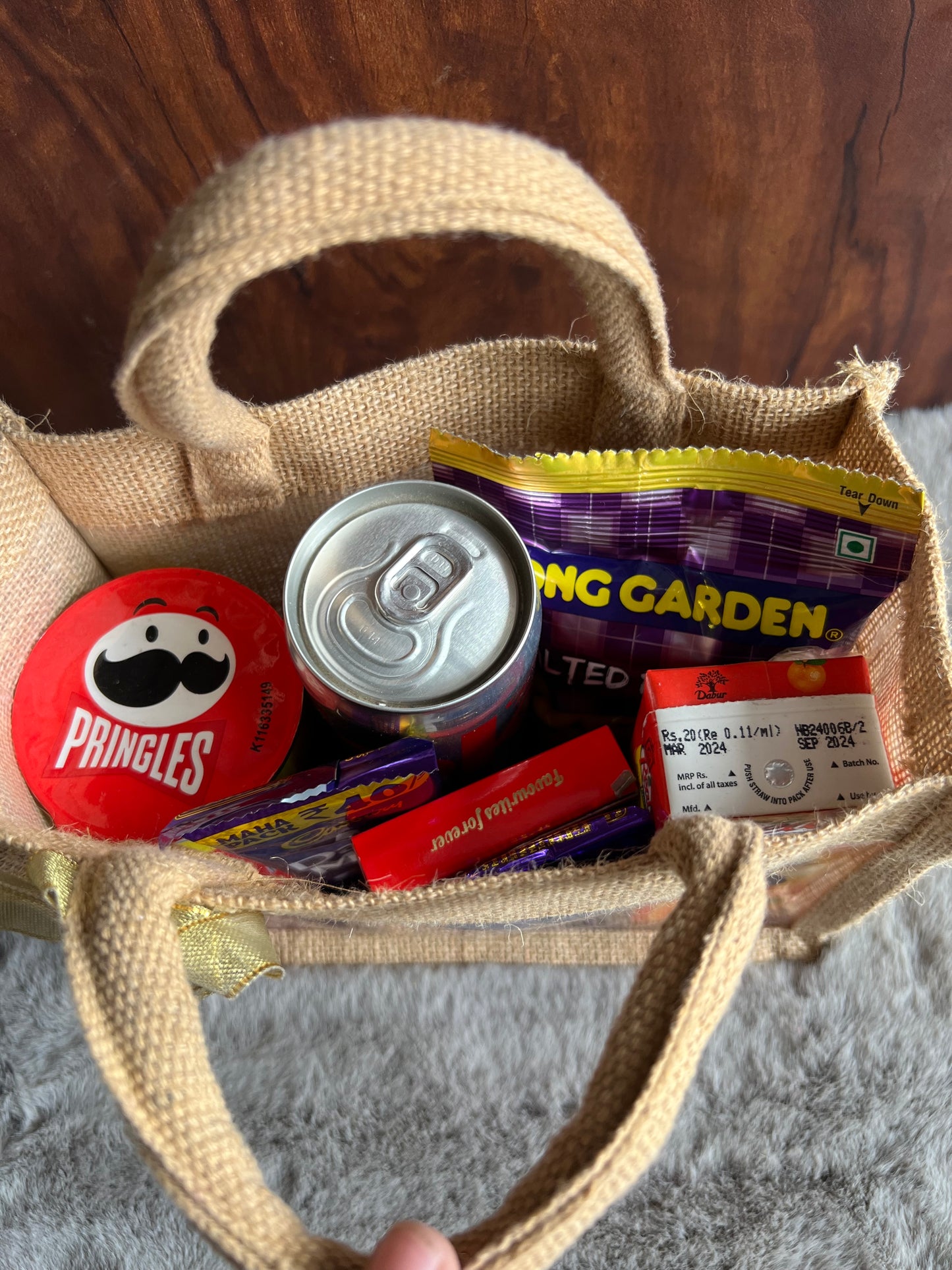 Snack Delight Rakhi Hamper with Pringles, Tong Garden Peanuts, Coke, Juice & Chocolates in Jute Gifting Bag