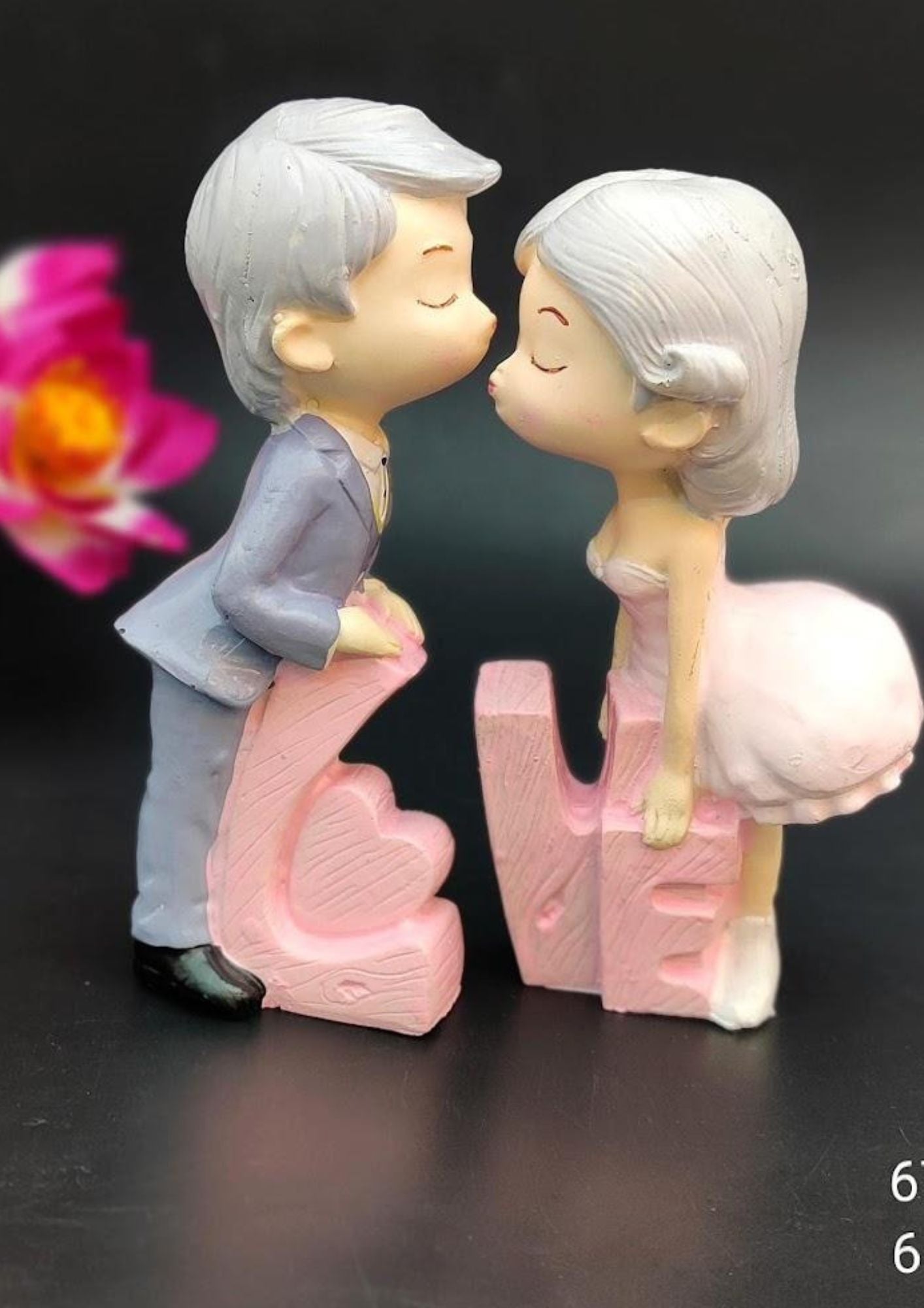 Kissing couple figurine with pink textured LOVE letters, featuring a boy in a grey suit and a girl in a pink dress, romantic decor and gift item.