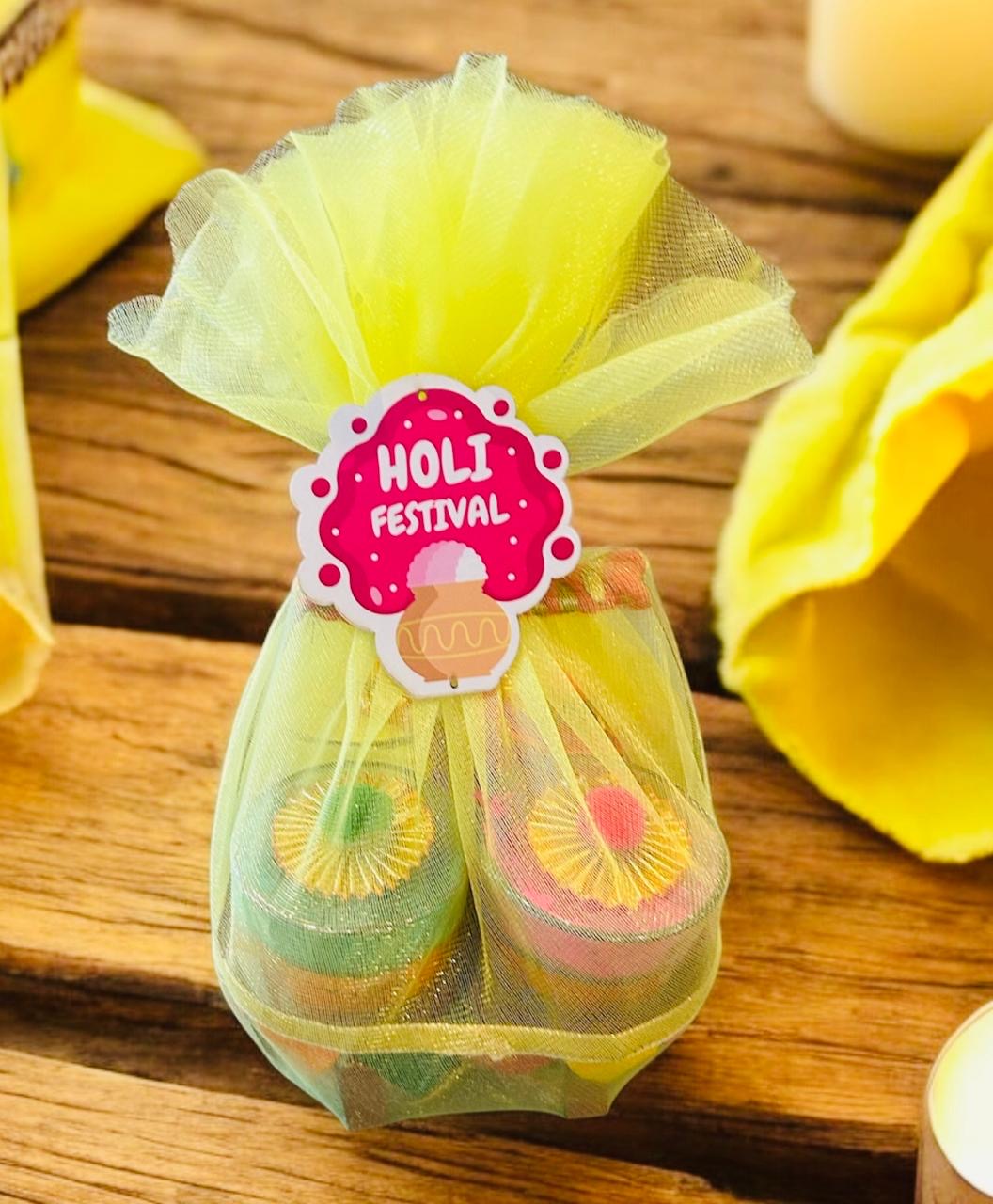 Holi hamper with four decorated tea glasses filled with gulal on a metal stand.