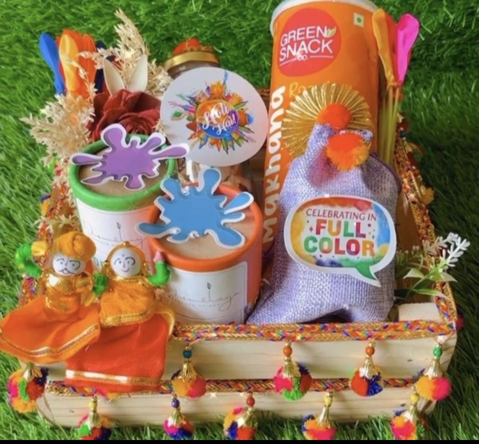 Holi Serenity Hamper: Nirmalaya Herbal Gulal, Makhana, Coated Dry Fruits, Water Balloons in Decorated Pinewood Basket