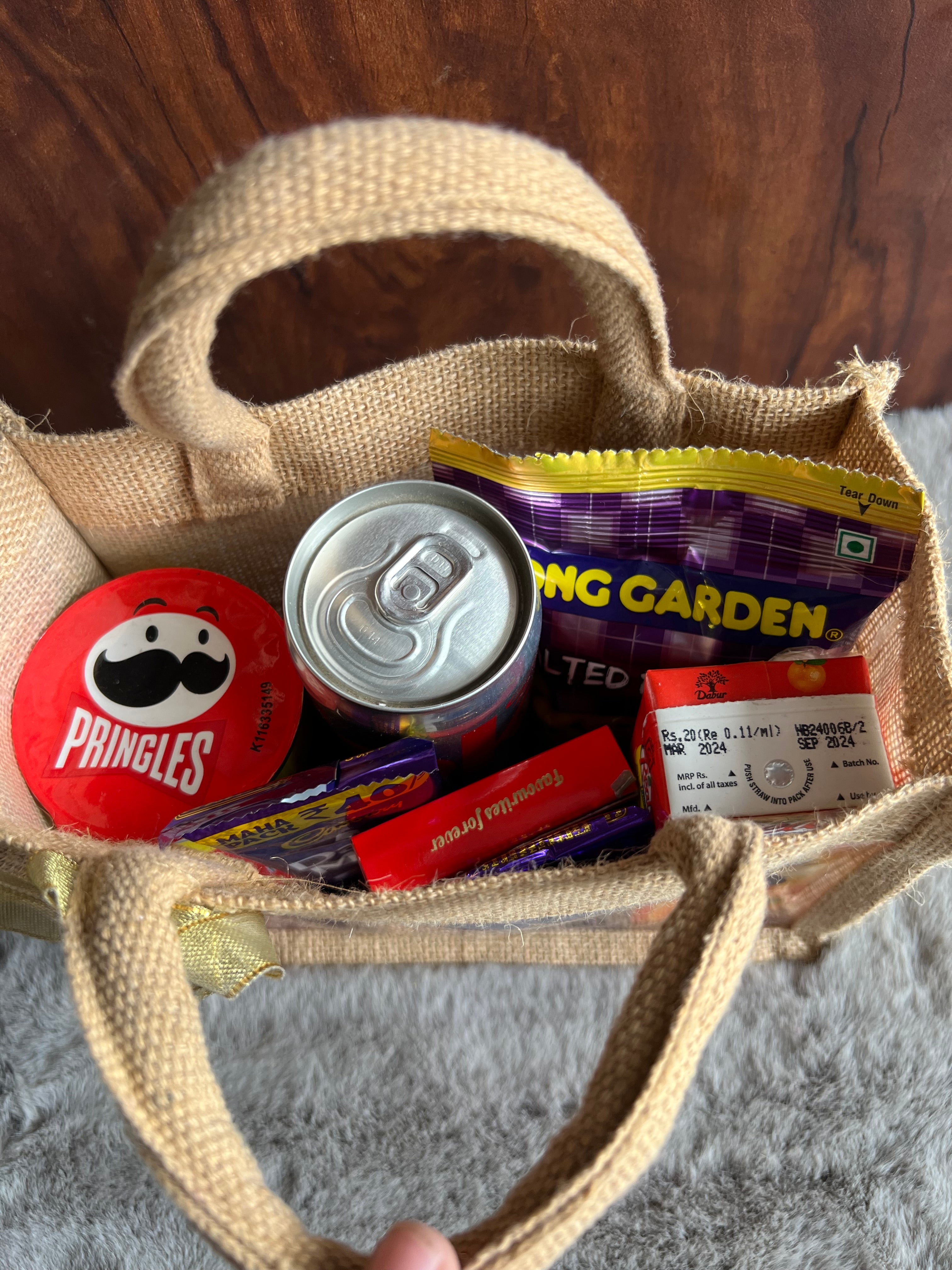 Snack Delight Rakhi Hamper with Pringles, Tong Garden Peanuts, Coke, Juice & Chocolates in Jute Gifting Bag