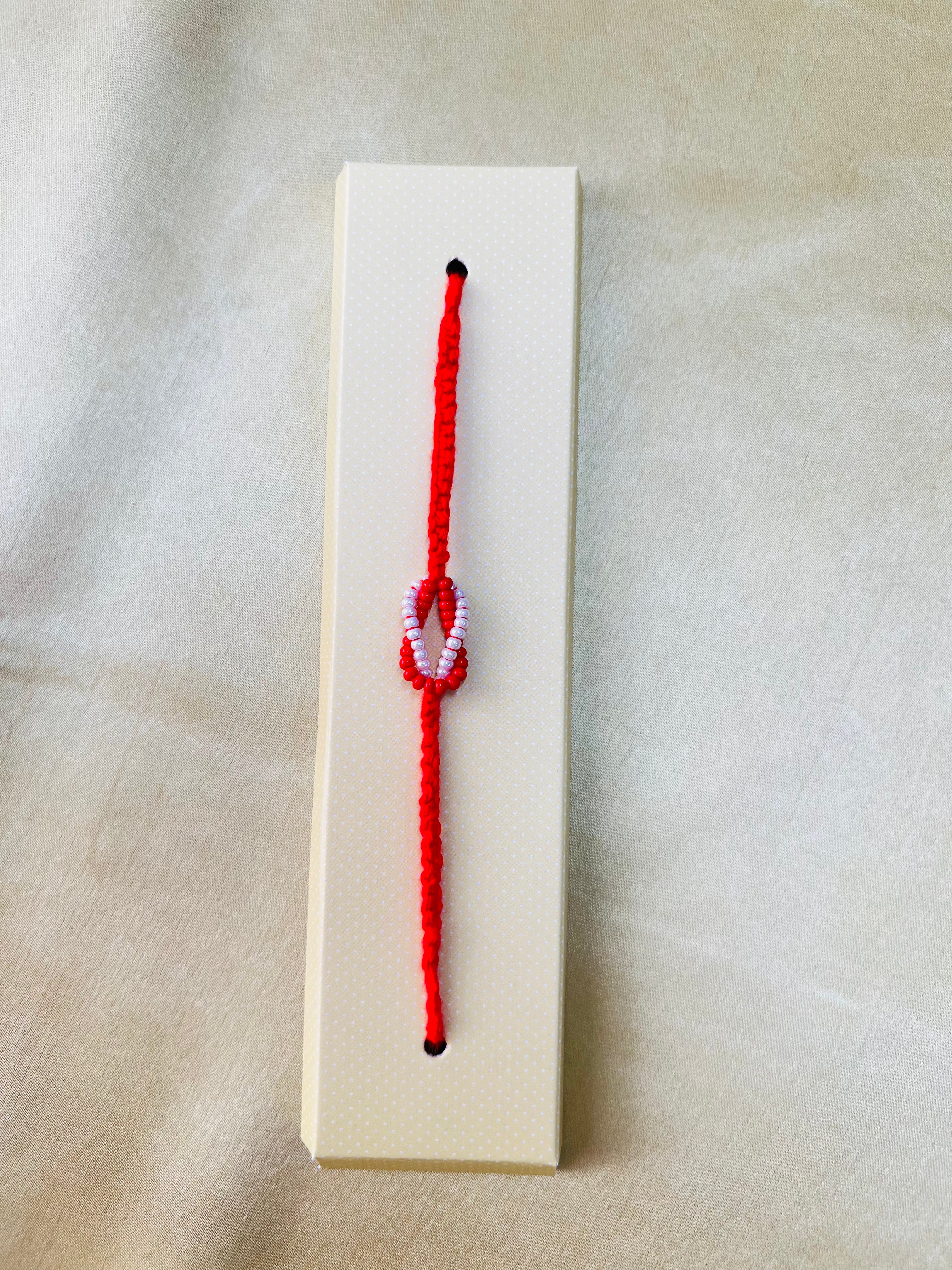 Wrap Shap RM801: Designer Beaded Rakhi with Red & White Infinity Symbol and Roli Chawal
