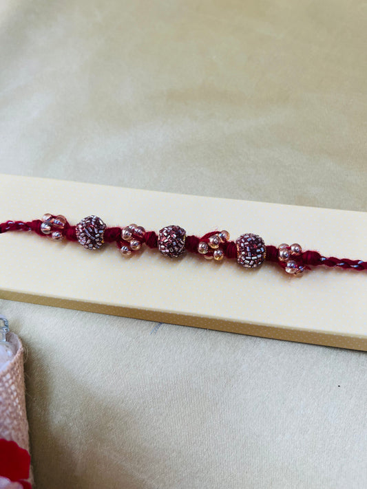 Wrap Shap RM811: Designer Crimson Beaded Rakhi with Decorative Elements and Roli Chawal