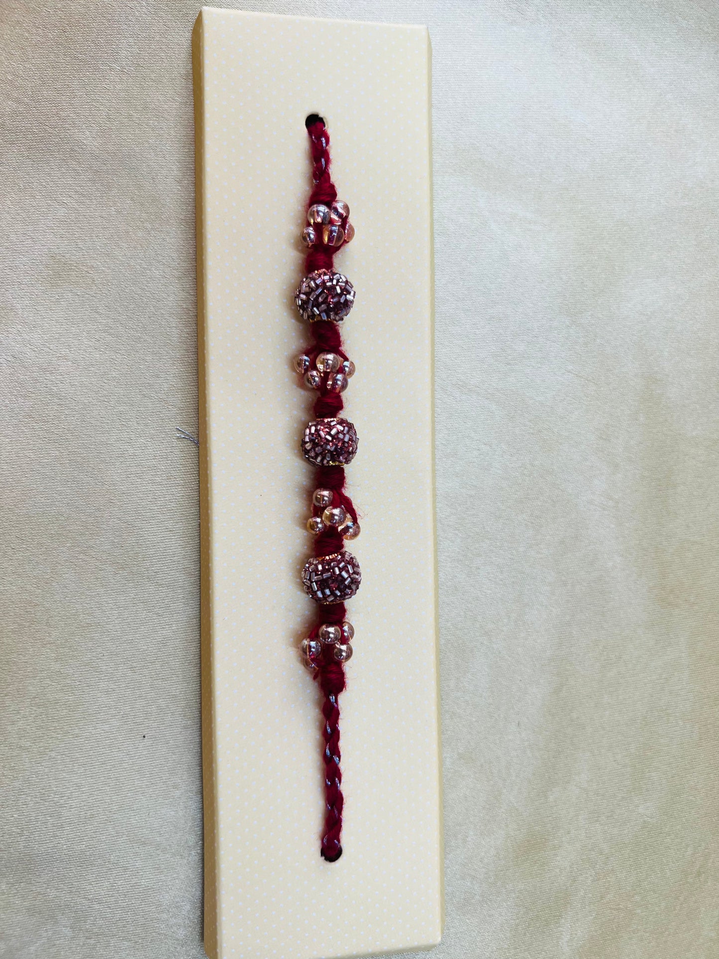 Wrap Shap RM811: Designer Crimson Beaded Rakhi with Decorative Elements and Roli Chawal