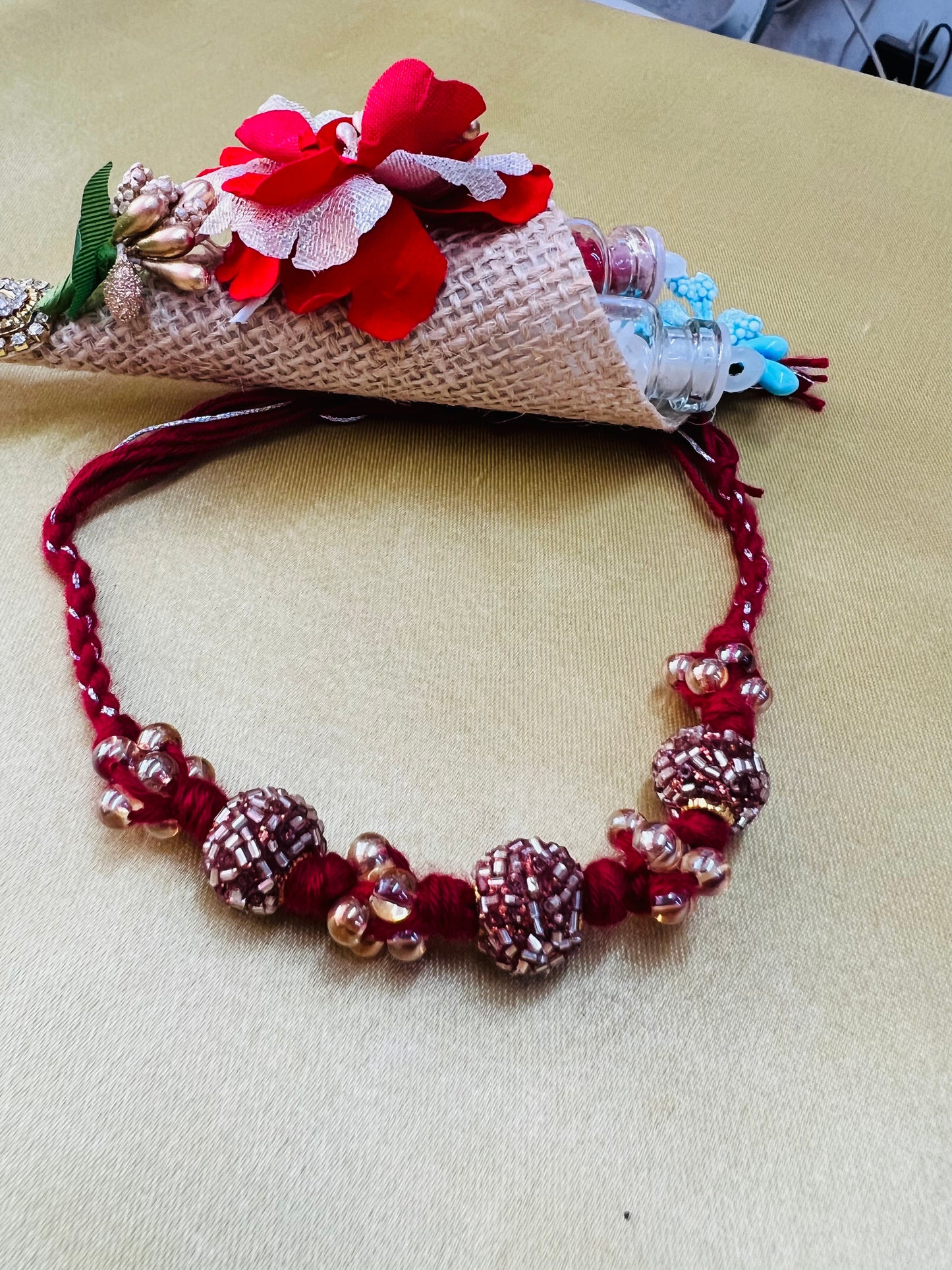 Wrap Shap RM811: Designer Crimson Beaded Rakhi with Decorative Elements and Roli Chawal