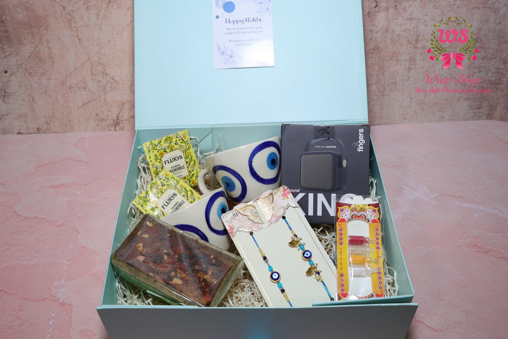 Bhaiya Bhabhi Rakhi Hamper with Evil Eye Tea Cups, Bluetooth Speaker, Tea Bags & Tea Cake in Gift Box | Wrap Shap