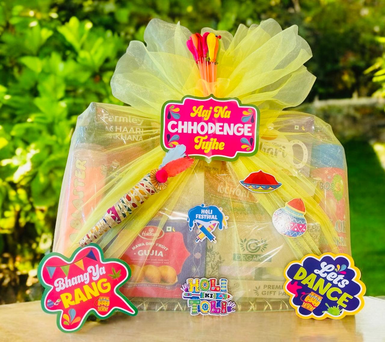 Holi celebration hamper with Gulal Blaster, organic gulal, snow spray, dry fruit gujiya, Shahi Thandai, and assorted snacks in a premium wooden tray.