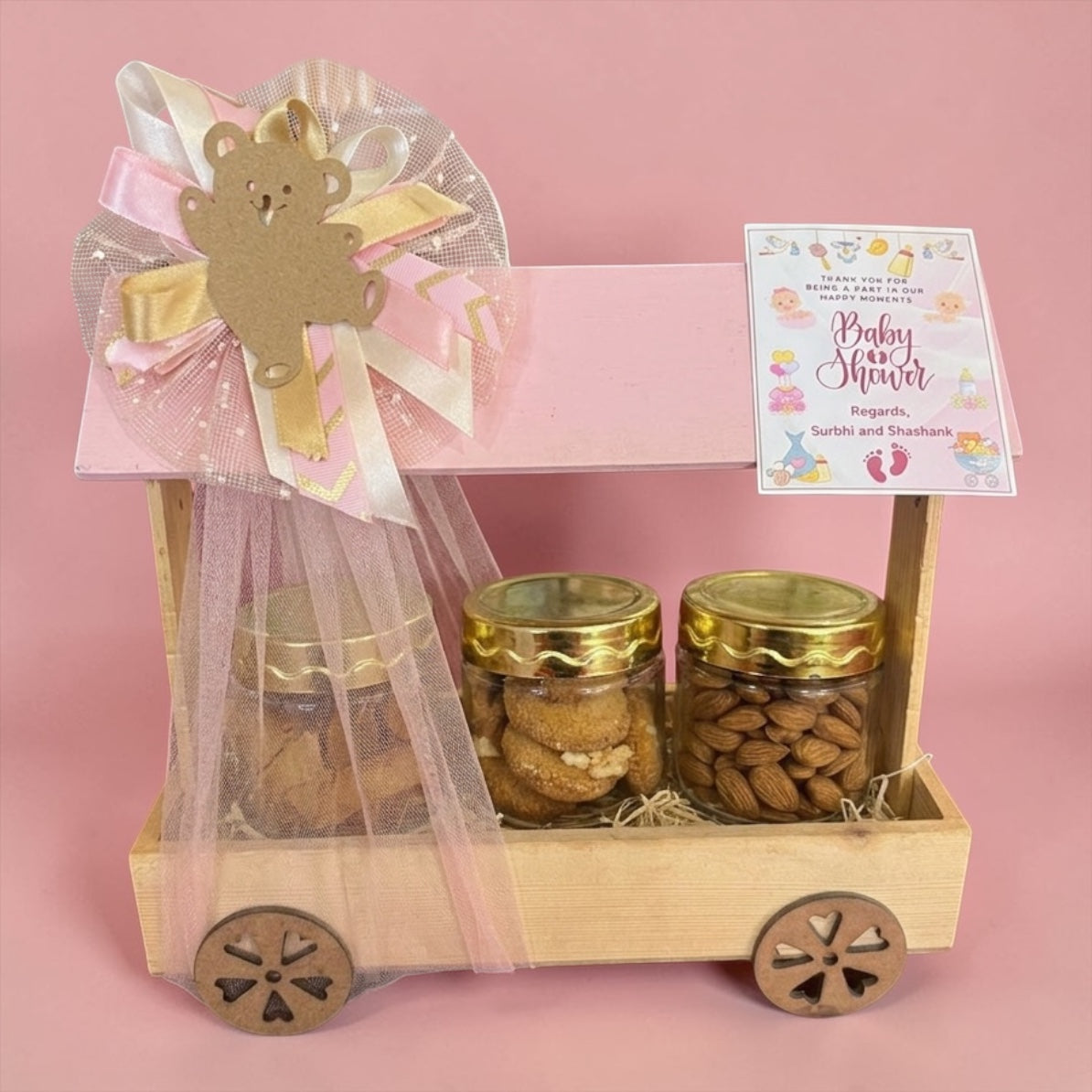 baby girl return gift hamper with cookies almonds and snacks in pink hut wooden basket