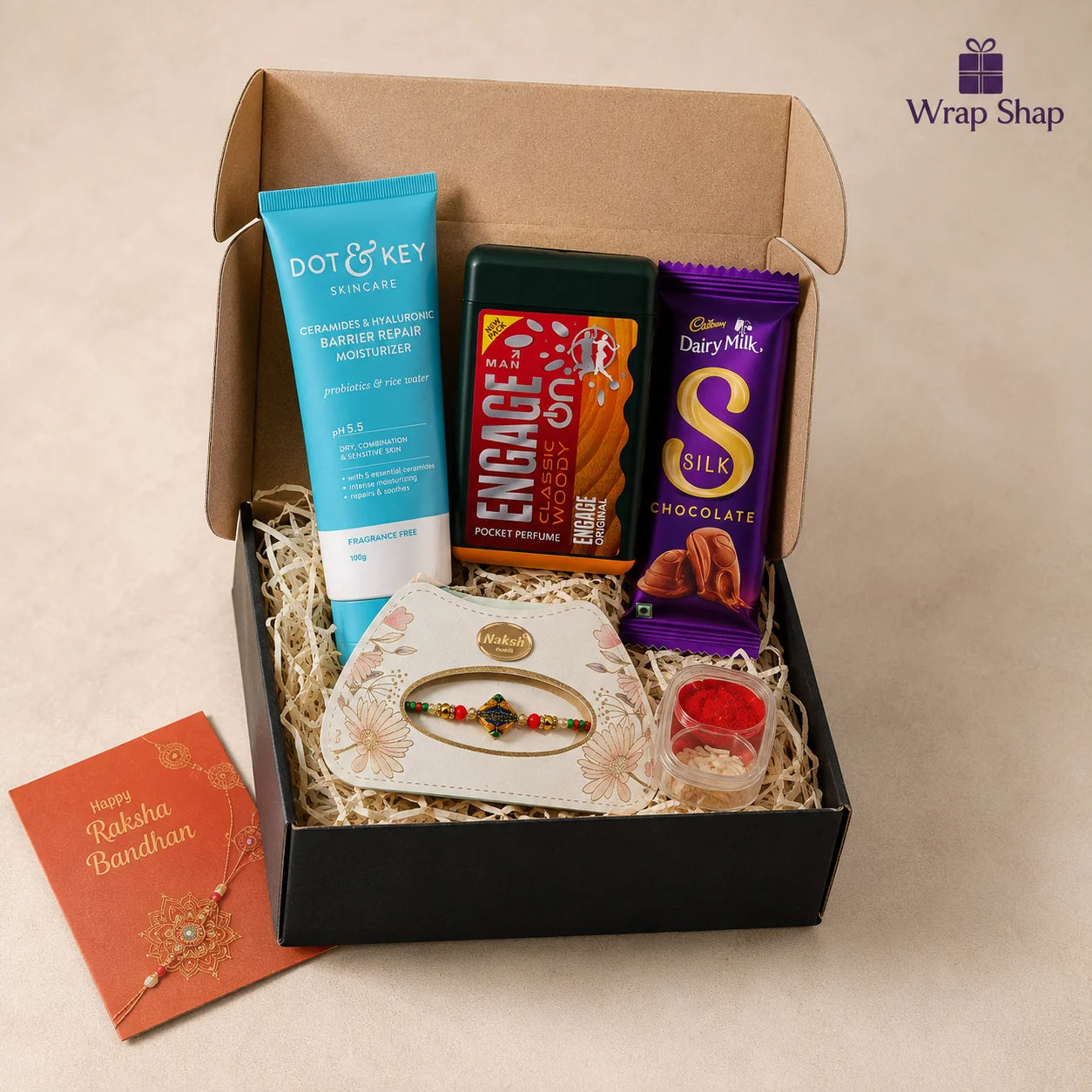 Premium Rakhi Grooming Starter Kit gift hamper for brother by Wrap Shap featuring a premium thread Rakhi, Engage pocket perfume, Dove & Key moisturiser, Cadbury chocolate, roli chawal, greeting card, and elegant gift box packaging for Raksha Bandhan.
