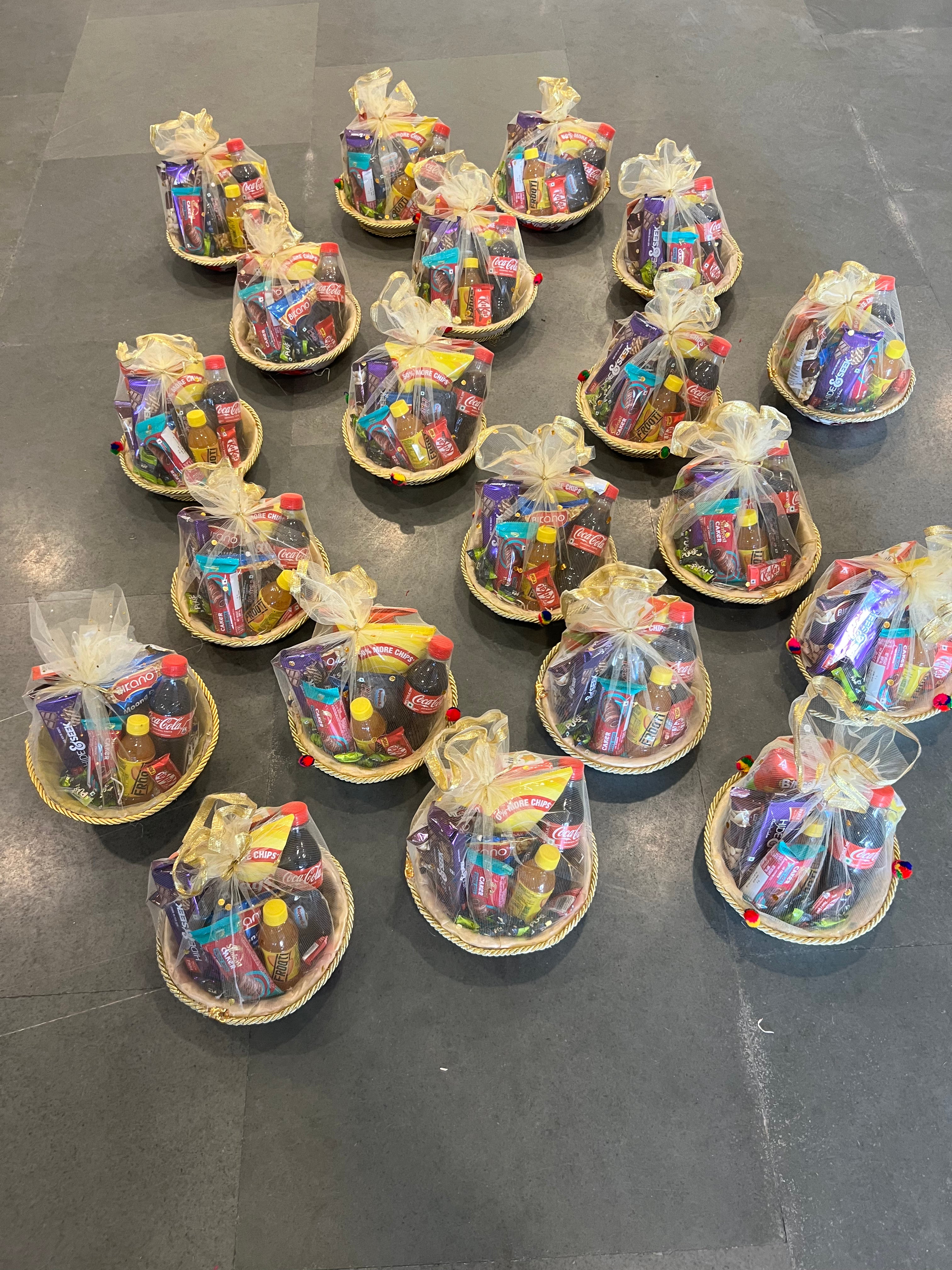 Affordable room hamper containing chips, biscuits, drinks and chocolates arranged in a net basket.