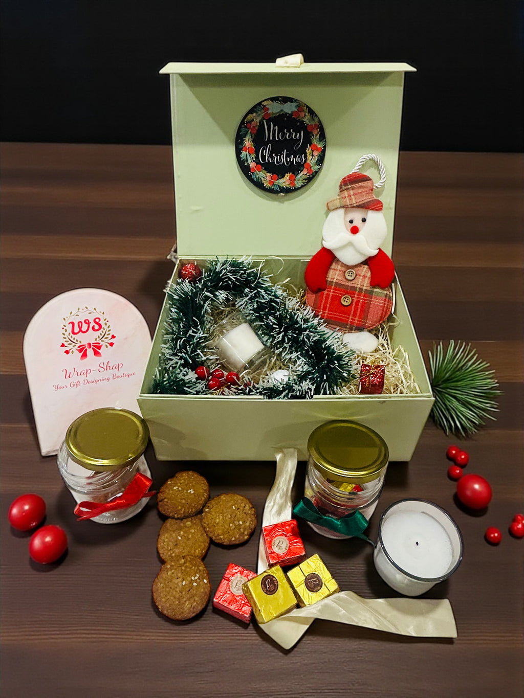 Christmas hamper in green gift box with freshly baked cookies, handmade chocolates and scented candles.