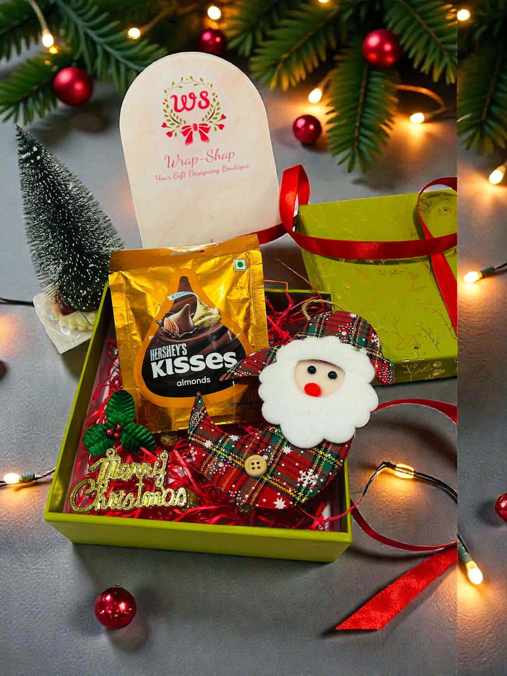 Christmas hamper in green gift box with table decor tree, Santa hanging and chocolate for kids