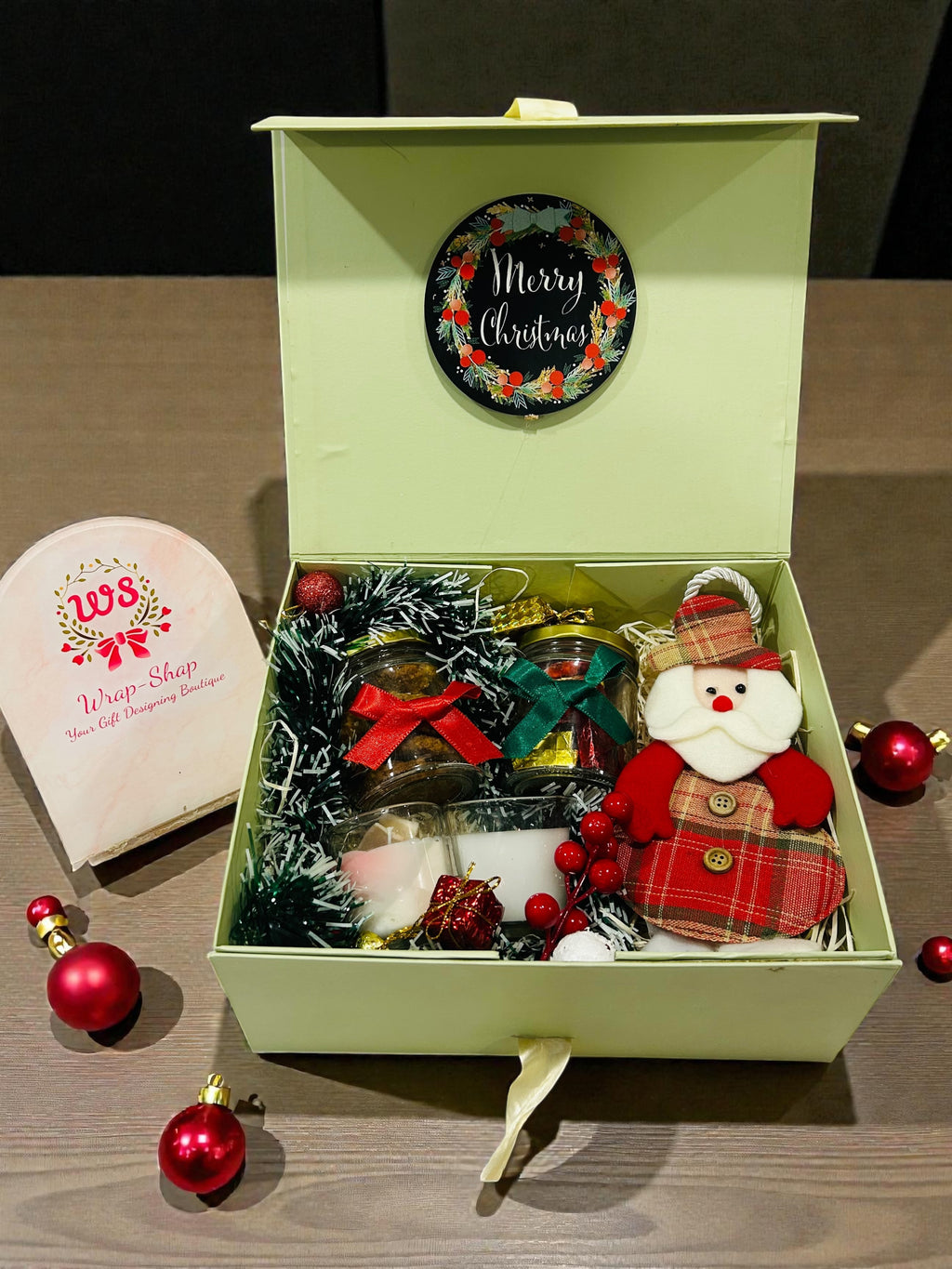 Christmas gift hamper with cookies, chocolates, two scented candles and tree decorative Santa.