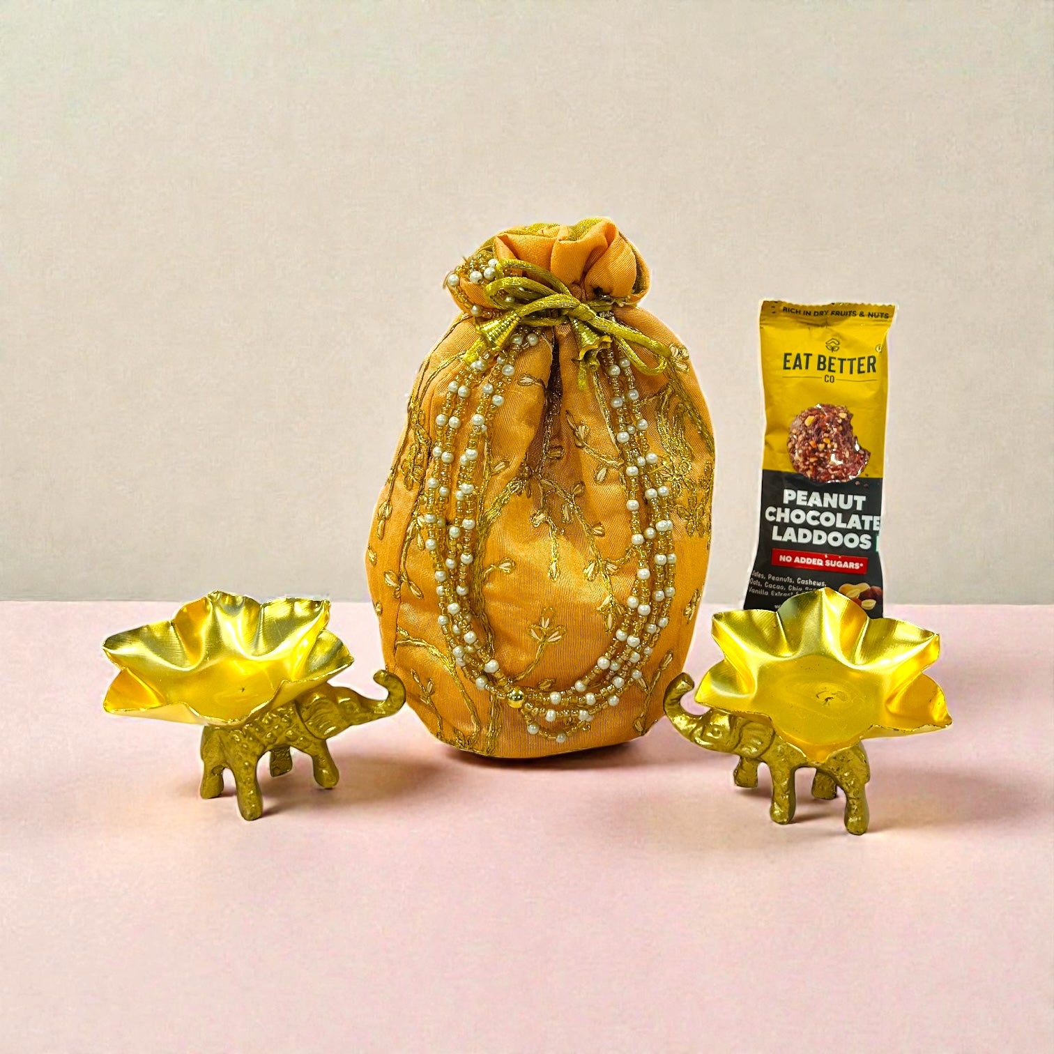 Return favour with elephant T-light holders and laddoo packed in embroidered batwa bag.
