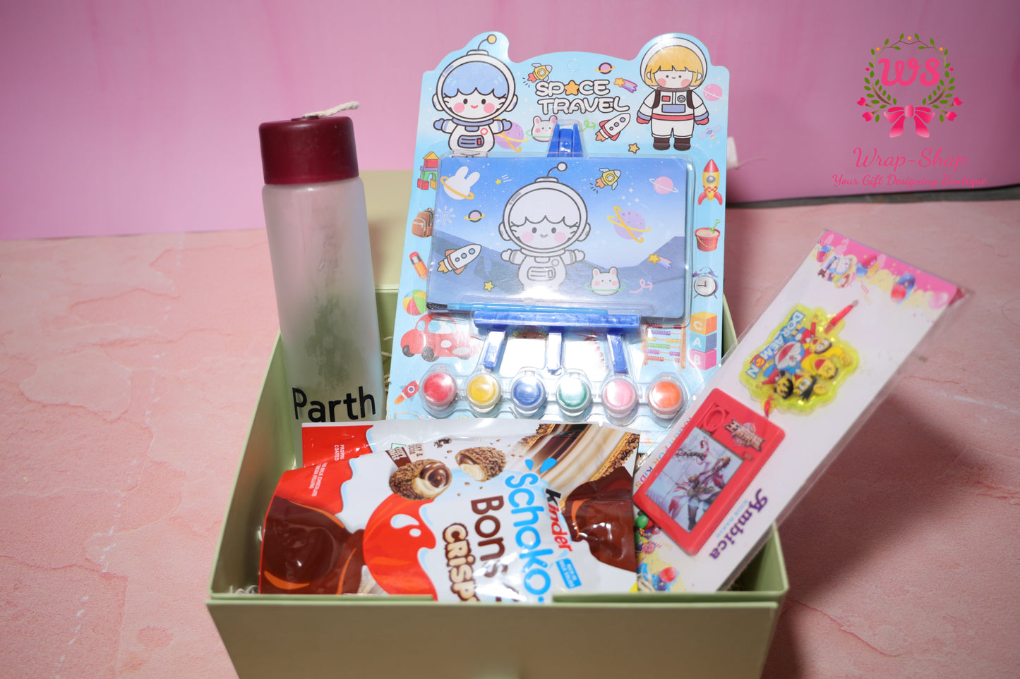 Wrap Shap Rakhi gift hamper for kids with painting kit, mini easel, personalized name glass bottle, kinderjoy Schoko Bons and rakhi in gift box