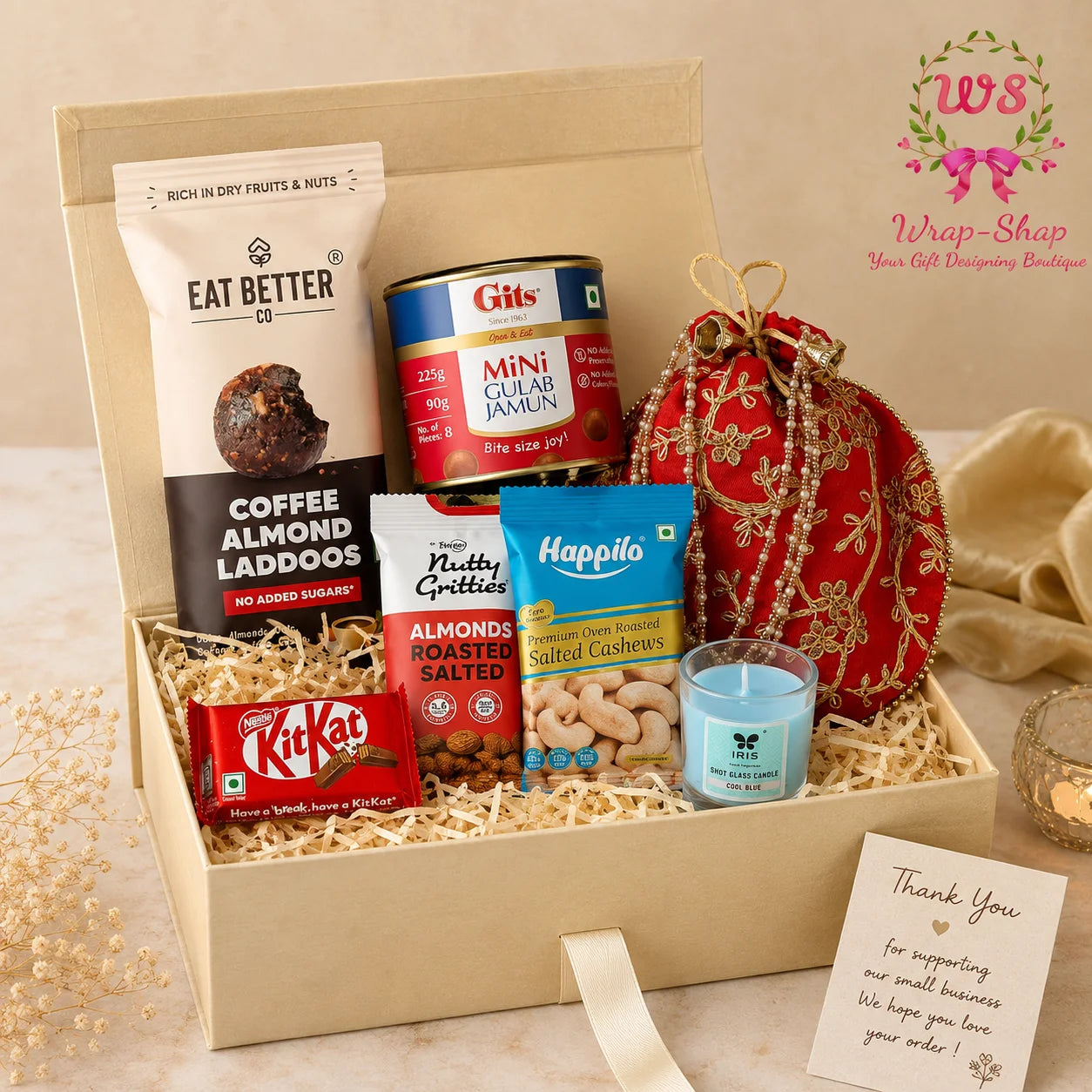 Classic Mithai Delight Box by Wrap Shap featuring Eat Better Laddoo, mini Gulab Jamun jar, cashew pack, almond pack, KitKat chocolates, shot glass candle, decorative potli batwa bag, handwritten thank-you card, and the Wrap Shap Signature Gift Box.