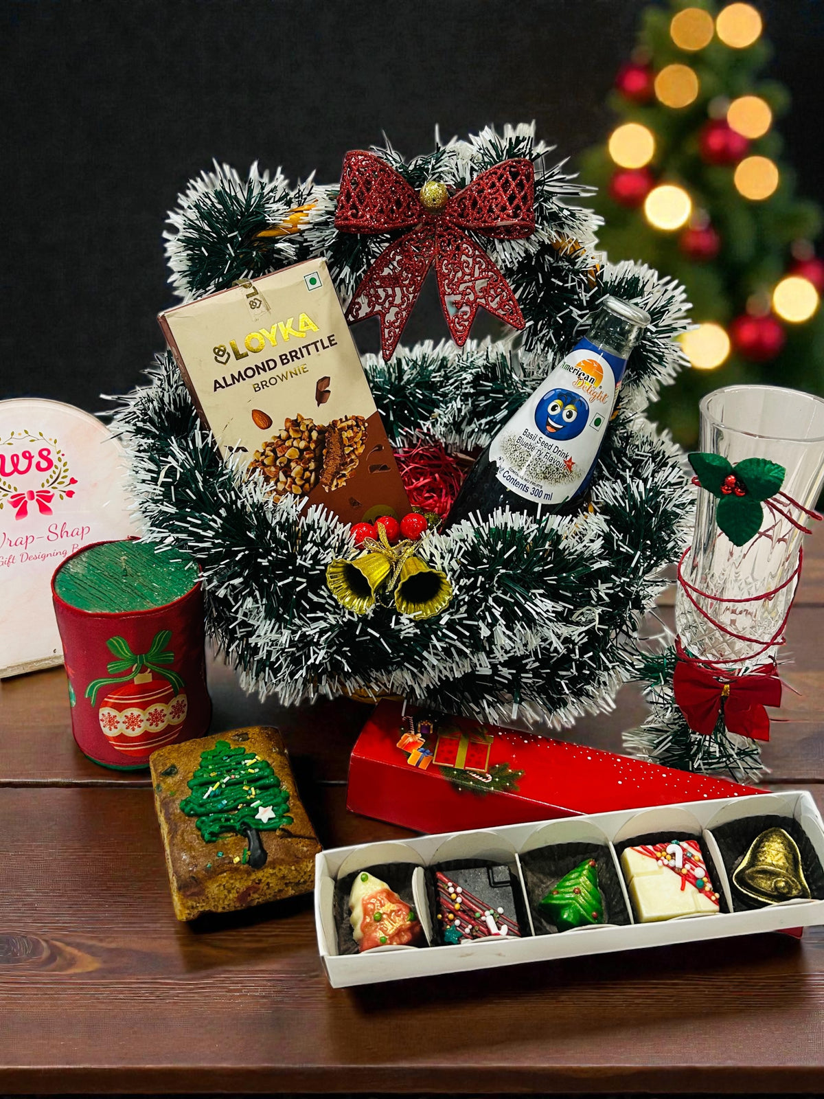 Premium Christmas gift hamper with chocolates, dry cake, drinks and festive décor in a decorated basket.