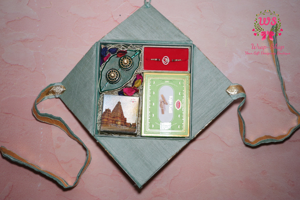 Wrap Shap Premium Rakhi hamper with Ganeshji frame, Kaju Katli sweet box, roli chawal platter and premium AD Rakhi in ethnic gift box