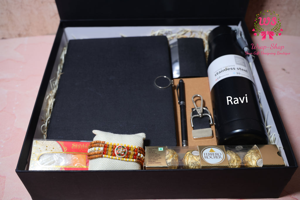 Wrap Shap Rakhi hamper with customized steel bottle, notebook, pen, card holder, keychain, Ferrero Rocher chocolates and Rakhi in rigid gift box