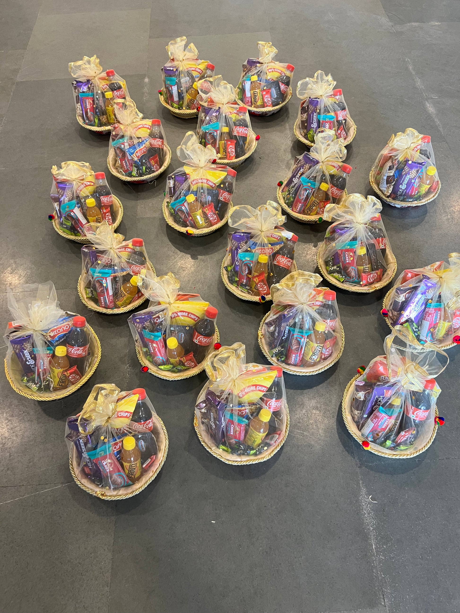 Low-cost snack hamper in round net basket with chips, beverages and assorted treats.