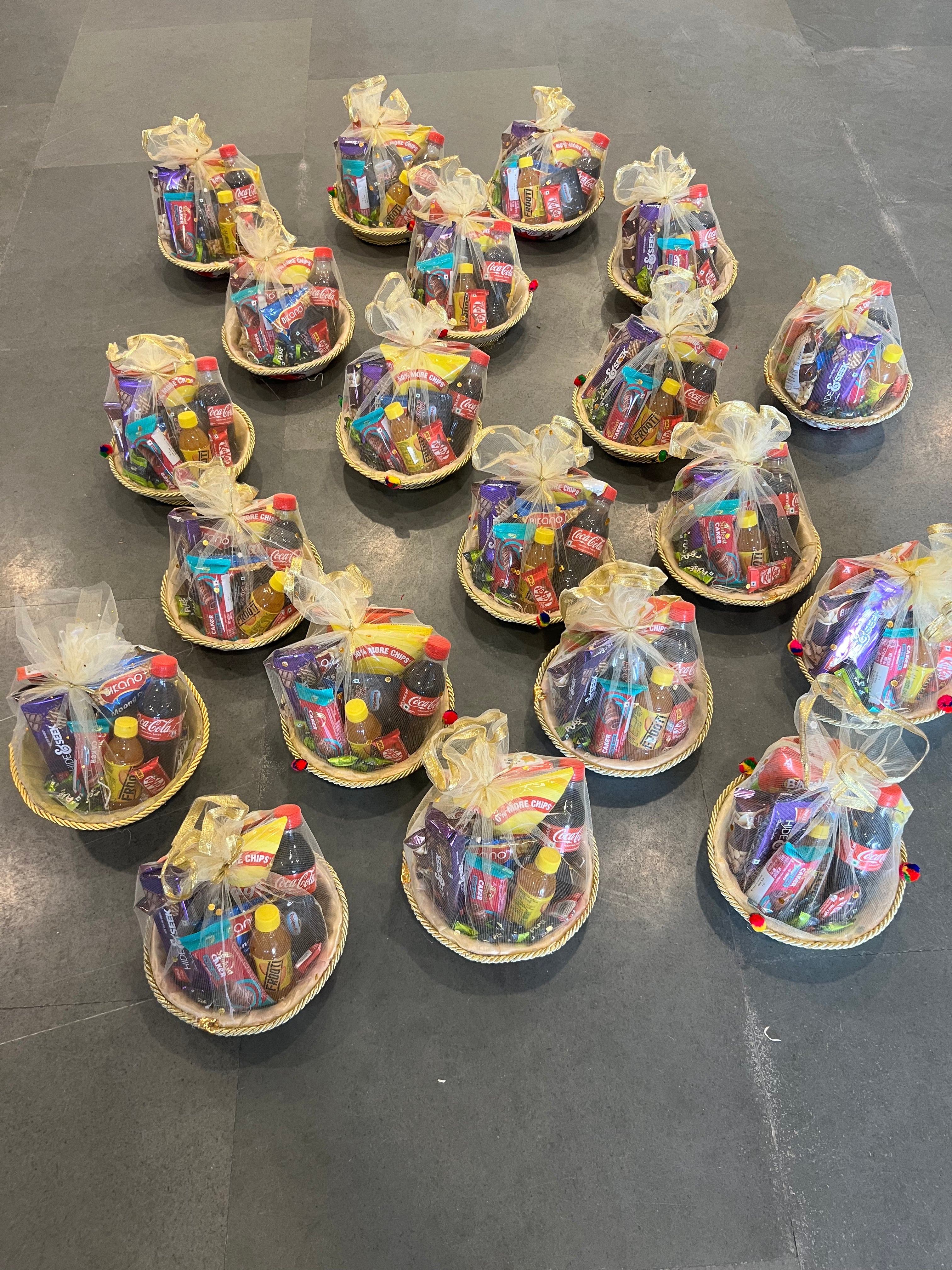 Low-cost snack hamper in round net basket with chips, beverages and assorted treats.