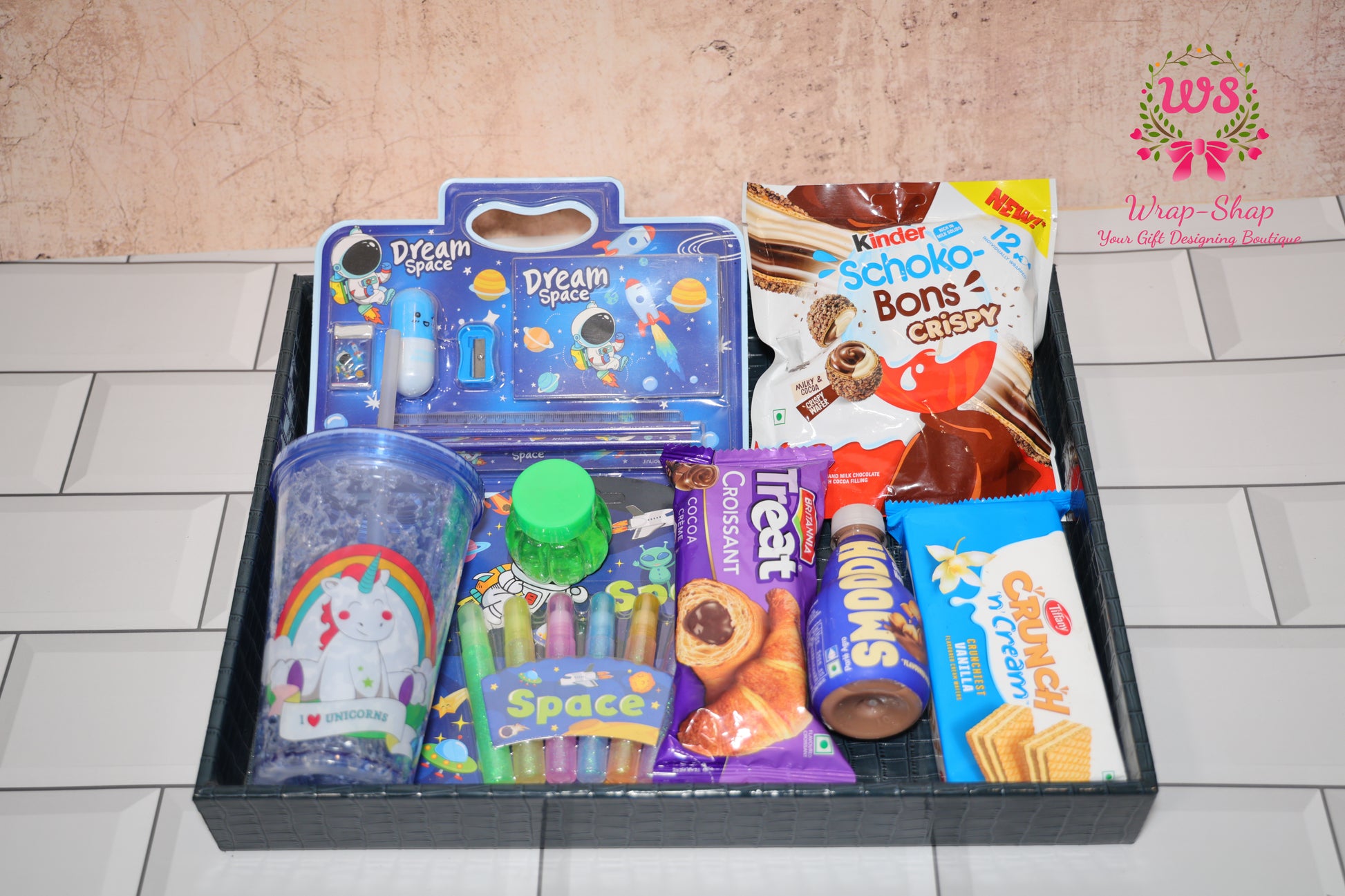 Wrap Shap space-themed gift hamper for boys with personalized tumbler, stationery, glitter, slime, chocolates, croissant and milkshake in leather tray