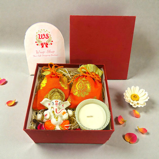 Wedding return favour with Ganesh statue, decorative candle and dry fruits in a rigid gift box.