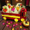 Wooden truck shape Lohri gift hamper with gajak, revdi, moongfali and popcorn in kite-decorated jute potlis.