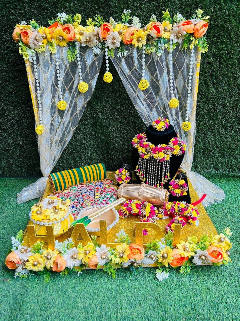 Wrap Shap Haldi & Mehendi platter with floral jewellery set, decorated mehendi cones, uptan pot, and colorful bangles on themed wooden tray