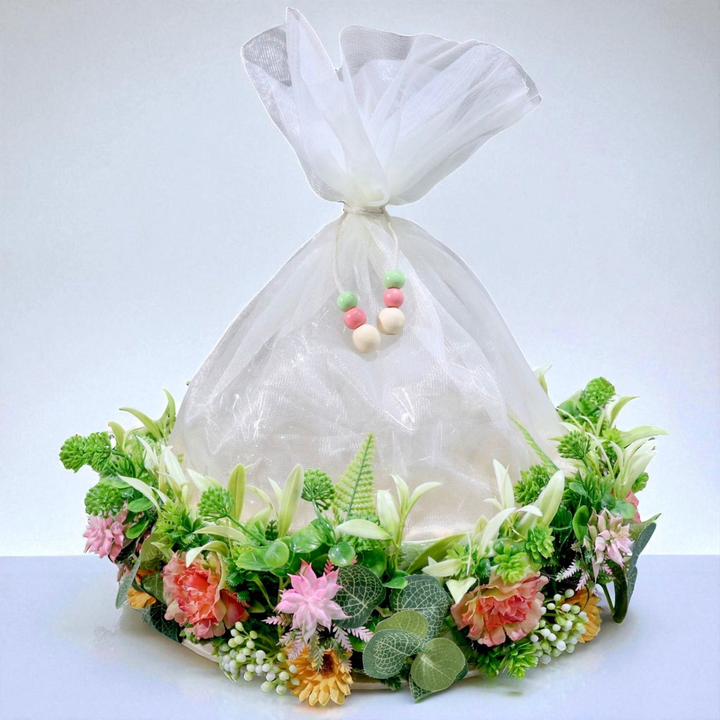 11-inch round gift basket decorated with artificial flowers, green leaves, and net cover, ideal for Indian festivals and gift hampers – by Wrap Shap