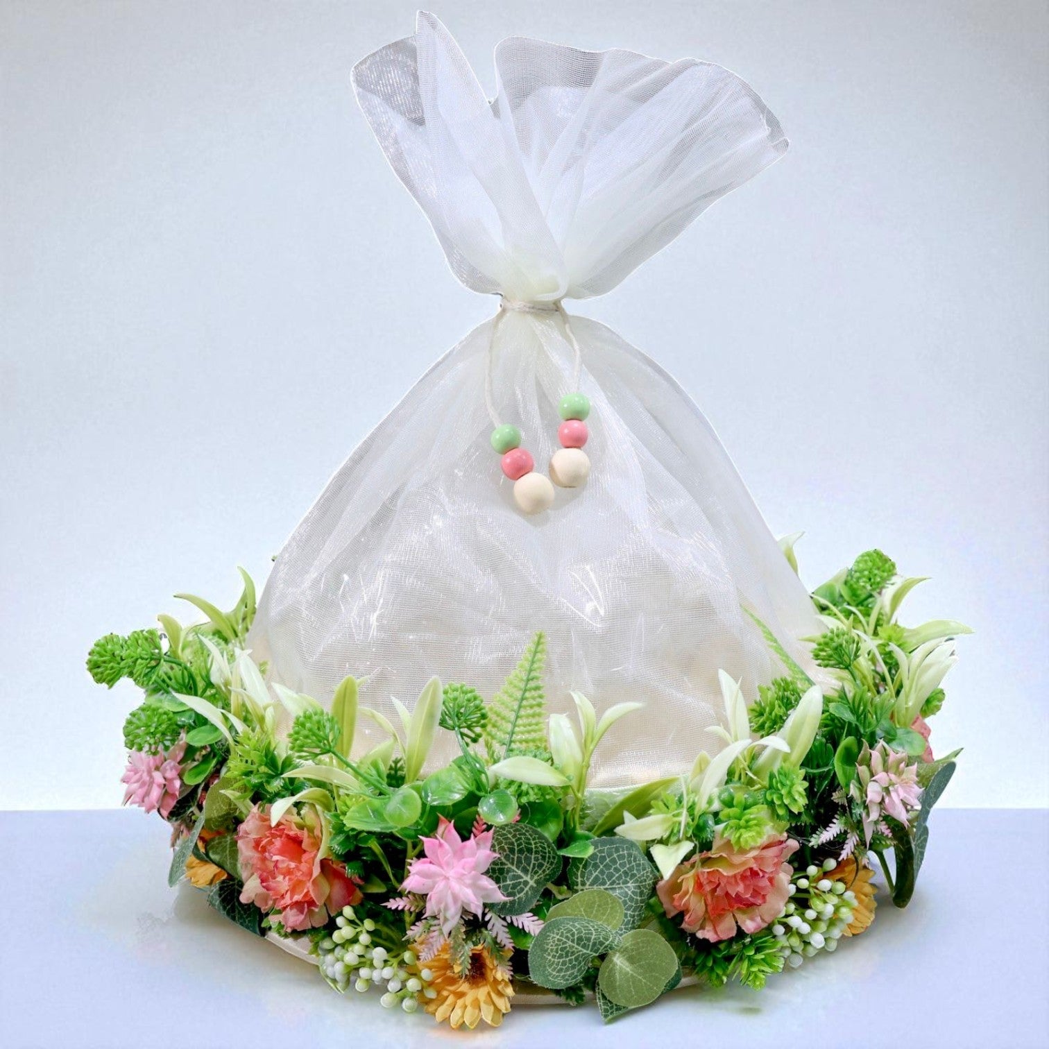 11-inch round gift basket decorated with artificial flowers, green leaves, and net cover, ideal for Indian festivals and gift hampers – by Wrap Shap